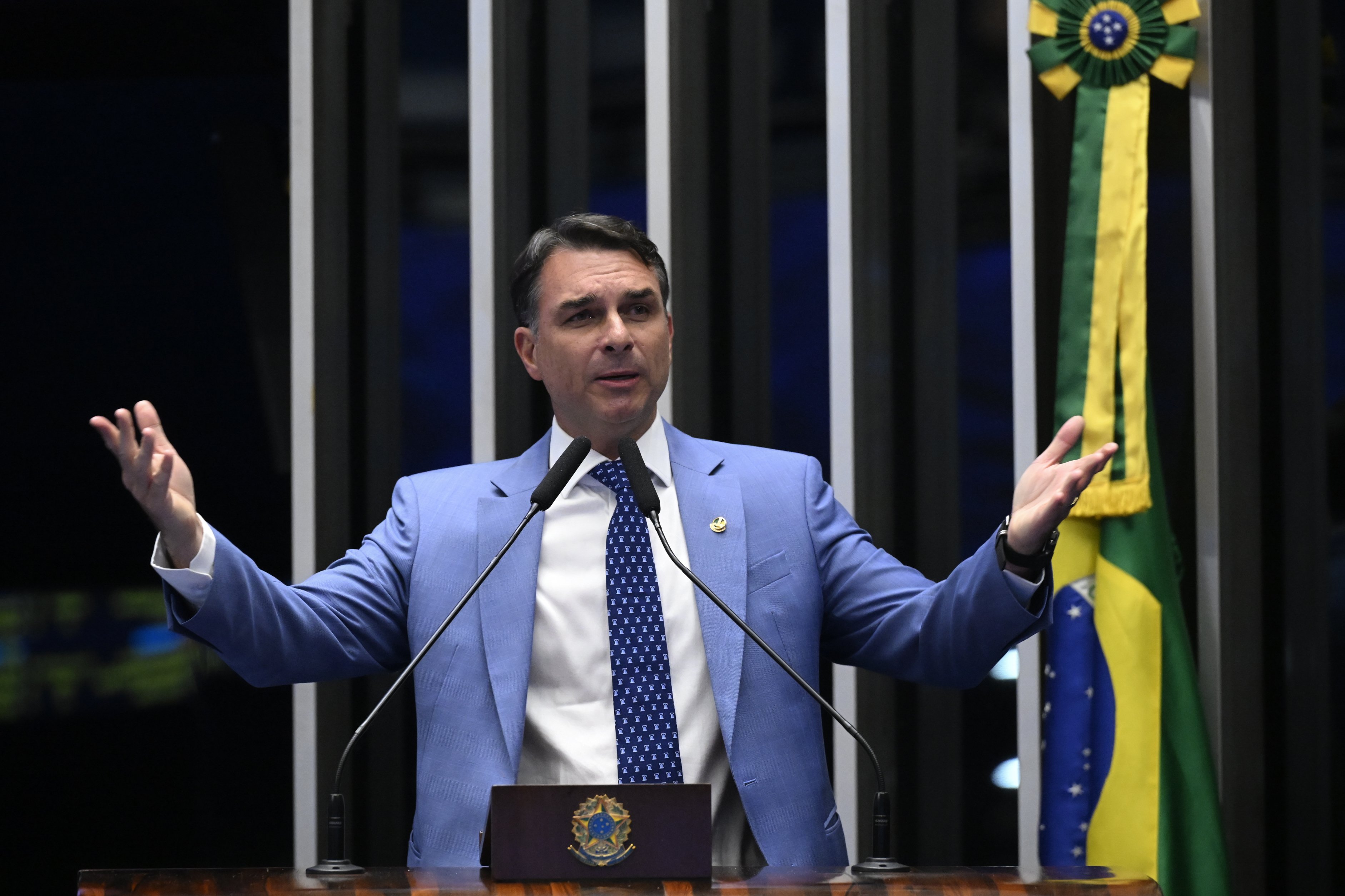 Carlos Moura/Agência Senado Flávio Bolsonaro discursa na tribuna do Senado, de terno azul, com a bandeira brasileira ao fundo. Foto de arquivo de 1º de setembro de 2026.